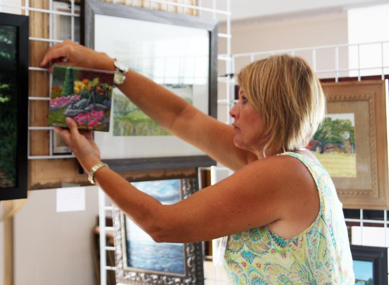 Charlene Mackiewicz of Wareham hangs up one of her pieces during Saturday's art show. BY MATTHEW BERNAT